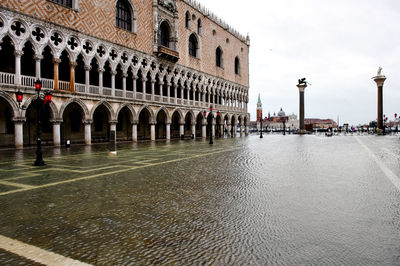 Water filled walkway by doges palace against sky