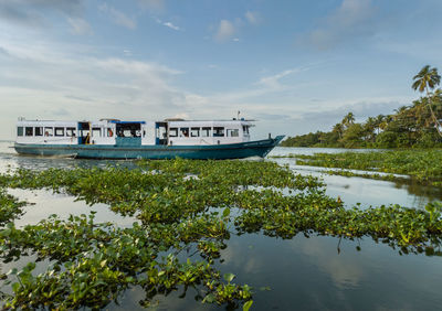 Boat moored on lake against sky