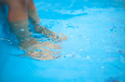 Low section of woman relaxing by swimming pool