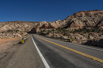 Road leading towards mountains against clear sky