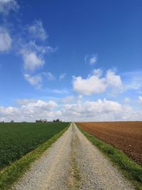 Road amidst field against sky