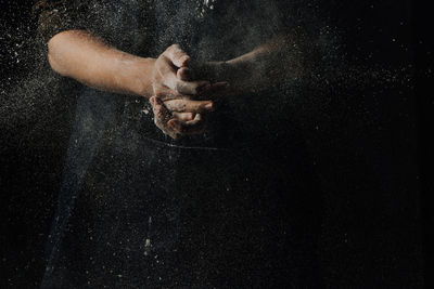 Close-up of hand withy flour over black background