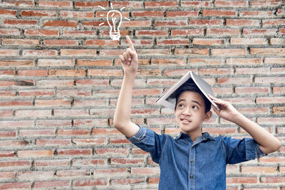 Portrait of boy holding stone against brick wall