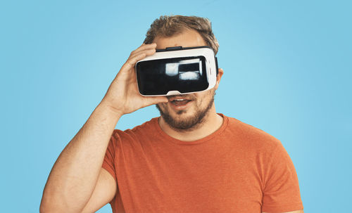 Man wearing virtual reality simulator against blue background