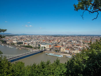 High angle view of river amidst buildings against blue sky