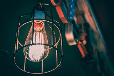 Low angle view of illuminated light bulb hanging on ceiling