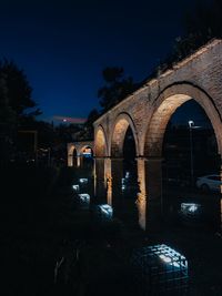 Arch bridge in city against sky at night