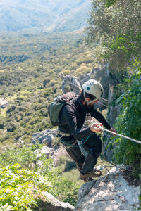 Adventure. man with helmet, harness and backpack. descending in the mountains by a via ferrata.