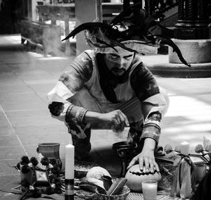 Full length of man sitting at street in city