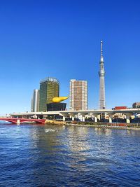 City at waterfront against blue sky