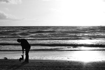 Man and dog on beach against sky