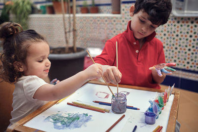 Children playing in an inner courtyard and painting with water paints