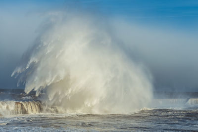 Water splashing in sea against sky