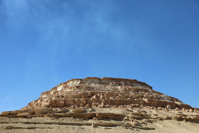 Low angle view of rock formation against clear blue sky