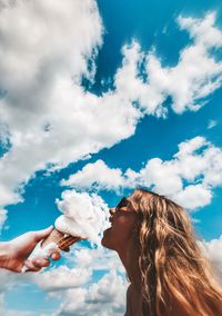 Optical illusion of woman eating cloud against sky
