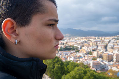 Close-up portrait of teenage girl with cityscape in background