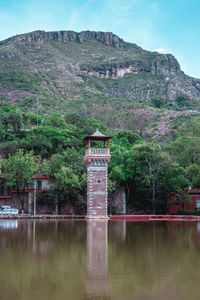  brick tower and wall in front of river with mountain in the background