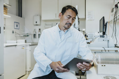 Male scientist using digital tablet while sitting at laboratory