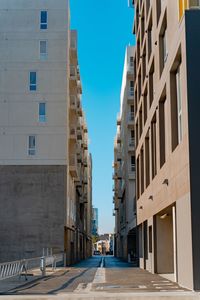 Street amidst buildings against clear blue sky