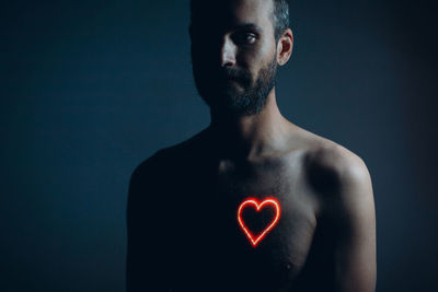 Portrait of shirtless man against black background