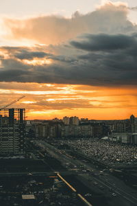 High angle view of railroad tracks by buildings against sky during sunset