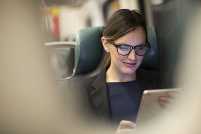 Happy businesswoman using tablet while traveling in subway train