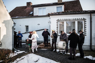 People standing outside house against sky