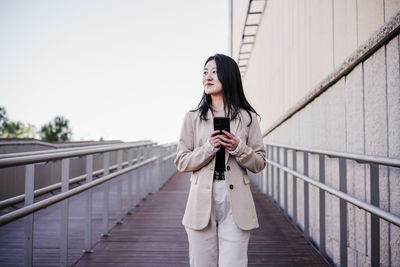 Confident beautiful chinese business woman using mobile phone in city. technology