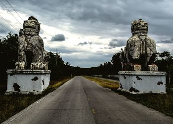 Statue by road against sky