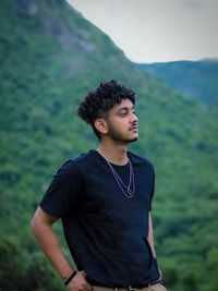 Young man looking away while standing on land