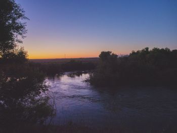 Scenic view of lake against clear sky at sunset