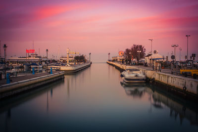 Boats moored at harbor against sky during sunset