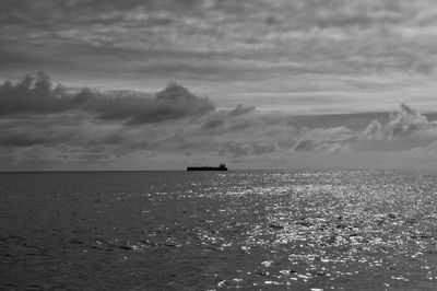 Boat sailing in sea against cloudy sky