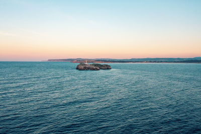 A small lighthouse on a stone rock in the sea near the coast