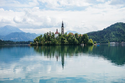 Scenic view of lake and building against cloudy sky