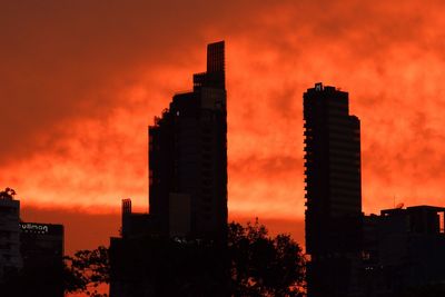 Low angle view of silhouette buildings against orange sky