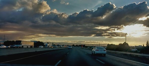 Cars on road against sky during sunset