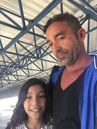 Portrait of father with daughter under shed