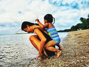 Rear view of shirtless boy on beach against sky