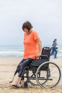 Man sitting at beach against sky