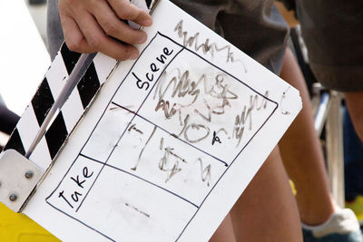 Midsection of man holding film slate while standing outdoors