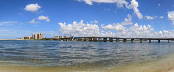 Bridge over sea and buildings against sky