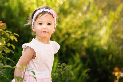 Cute girl looking away while standing against plants