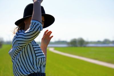 Young woman standing on field against sky