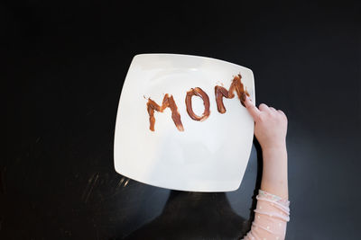 Midsection of woman holding ice cream against black background