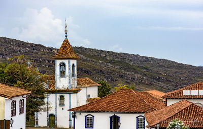 Historic church with rising through the trees and roofs and mountains of the town of diamantina