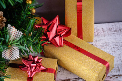 Close-up of christmas tree and presents against gray wall