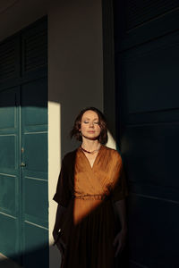 Woman with eyes closed standing by door in resort at deauville, france