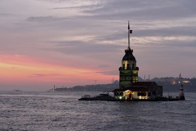 Building by sea against sky during sunset