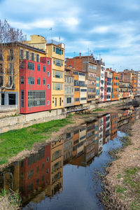 Buildings by river against sky